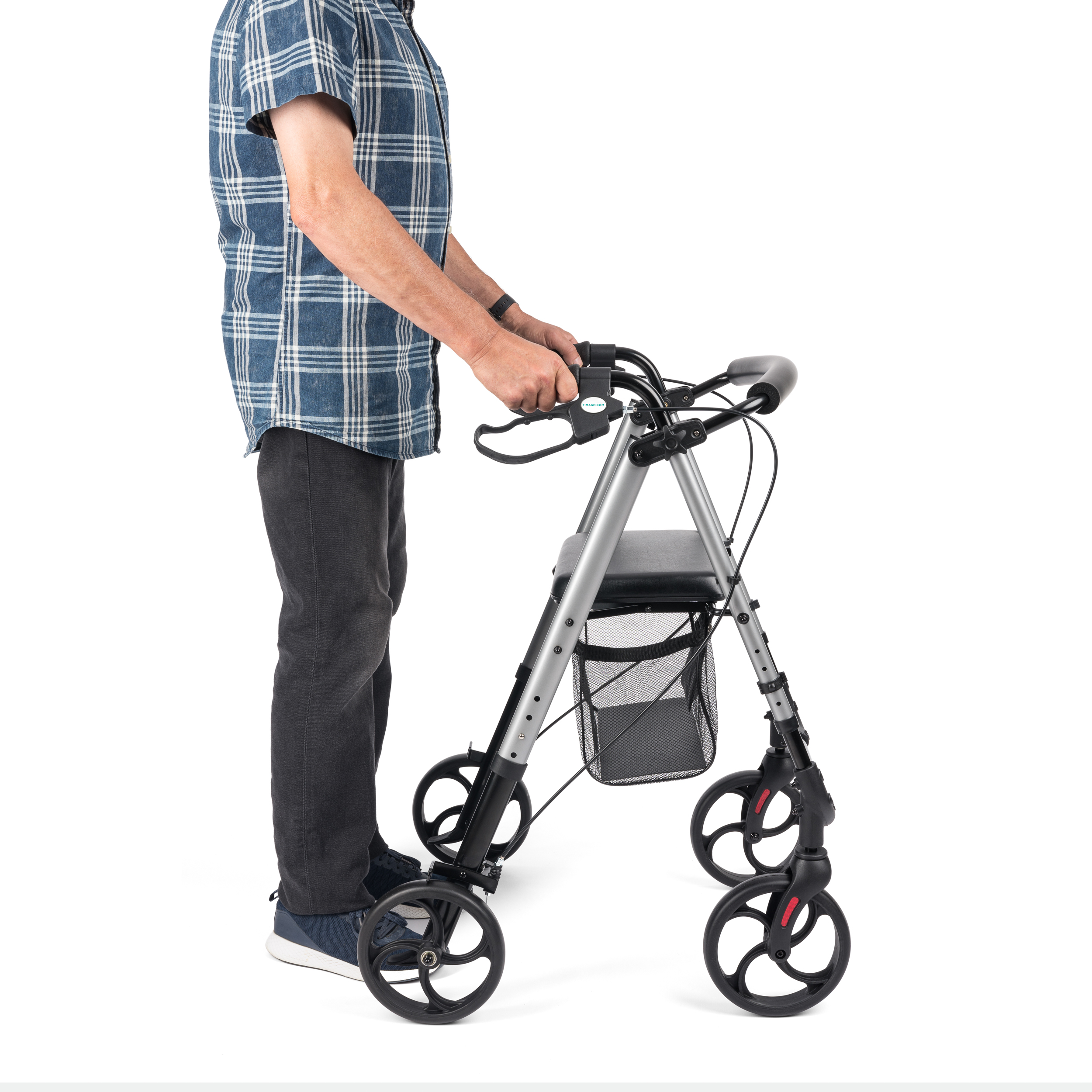 rolator_alina_2 - fizio trgovina person in a blue plaid shirt pushing a four‑wheel rollator walker with a front mesh basket, seen from the side.