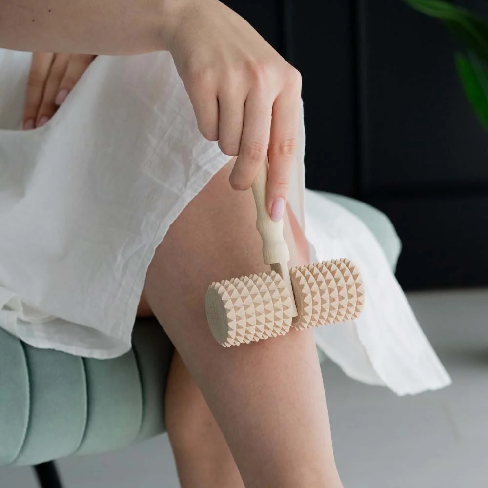 masazni_valjcek_10 - fizio trgovina person rolling their knee with a beige spiked massage roller on display table or lap area.