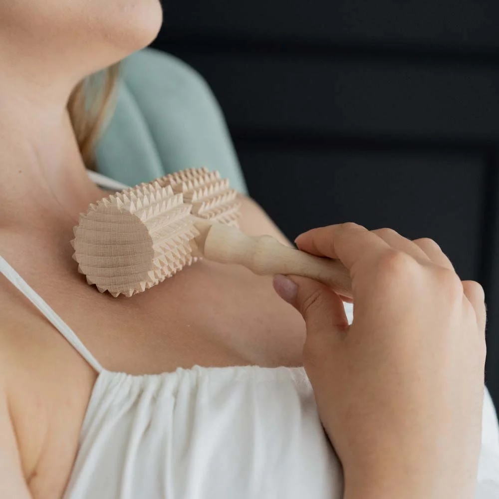masazni_valjcek_9 - fizio trgovina person using a wooden ribbed massage roller along the collarbone and shoulder area.